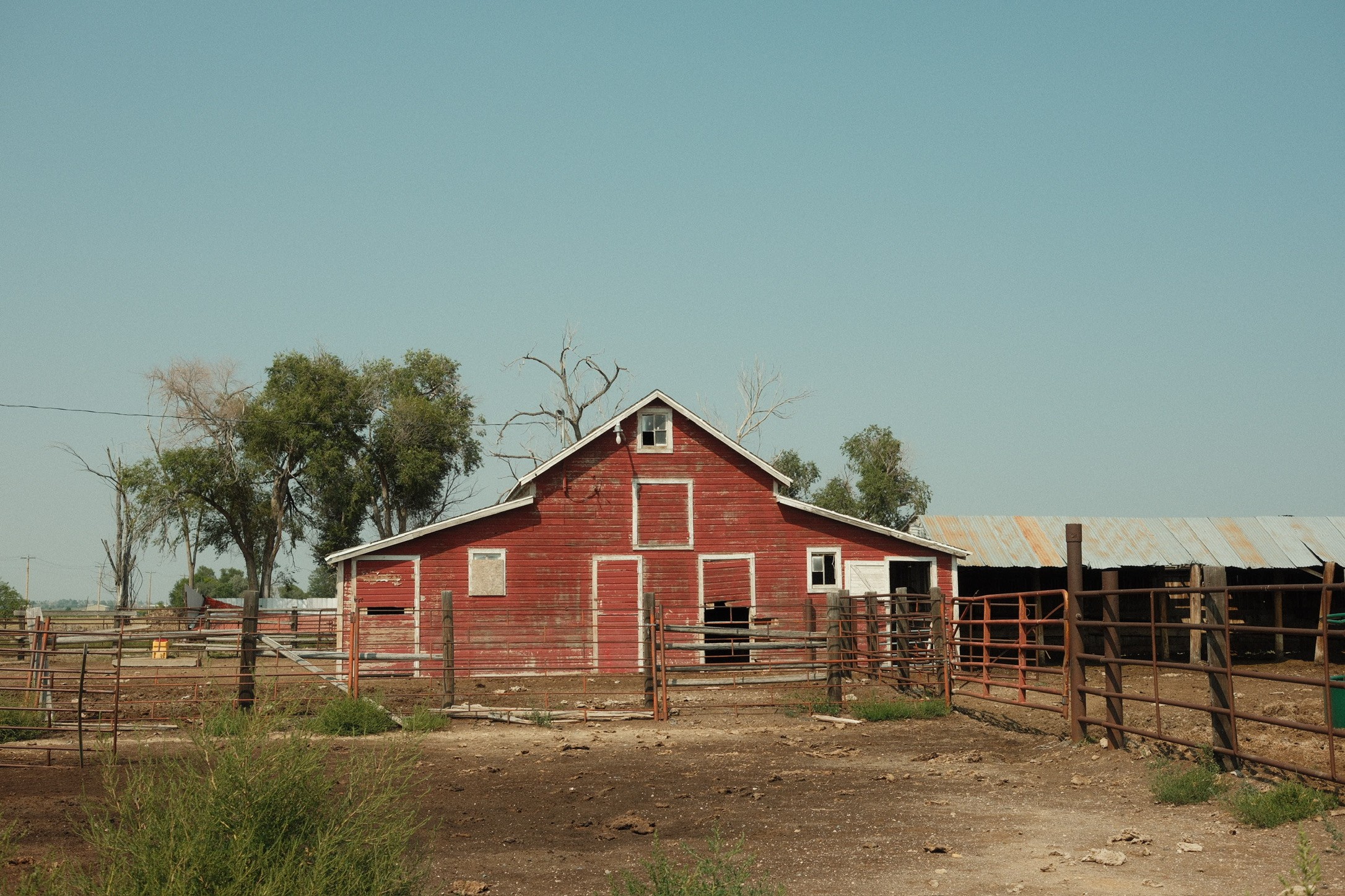 Weathered red barn with corrals under a clear sky