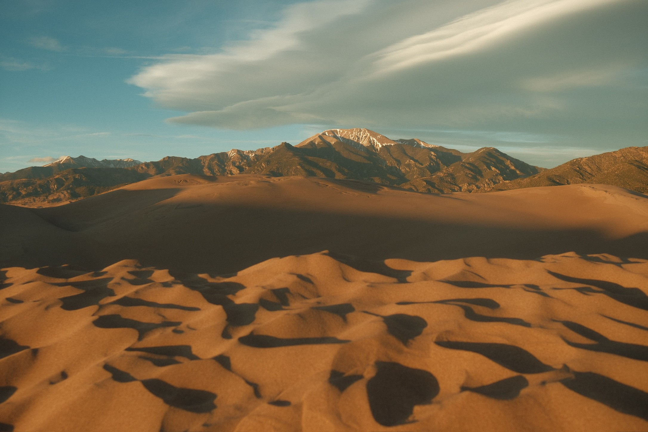 Great Sand Dunes at golden hour with snow-capped peaks behind