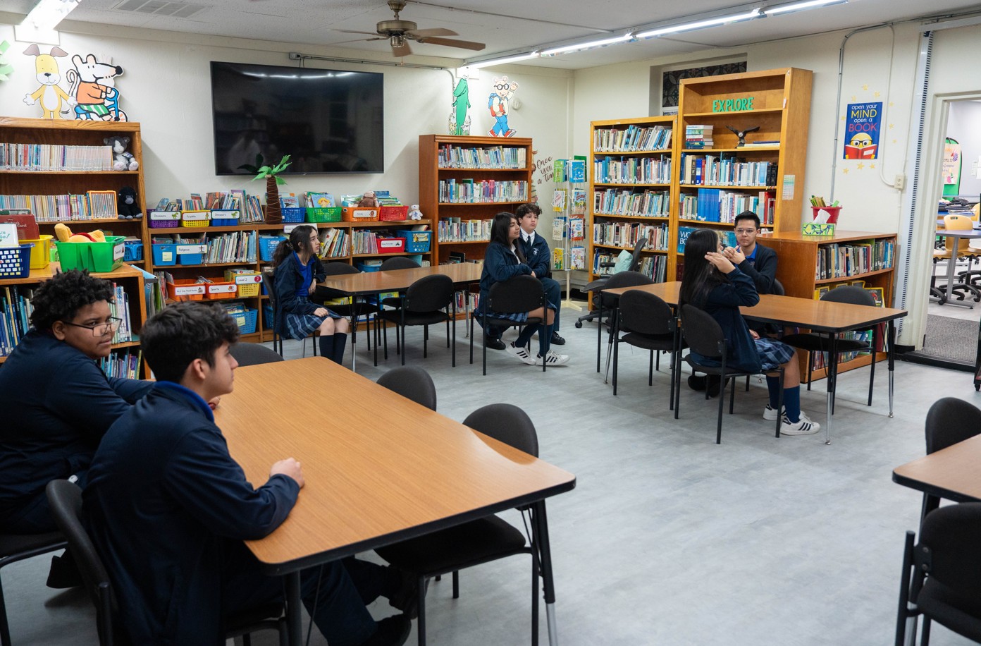 Students in uniforms seated at tables in school library