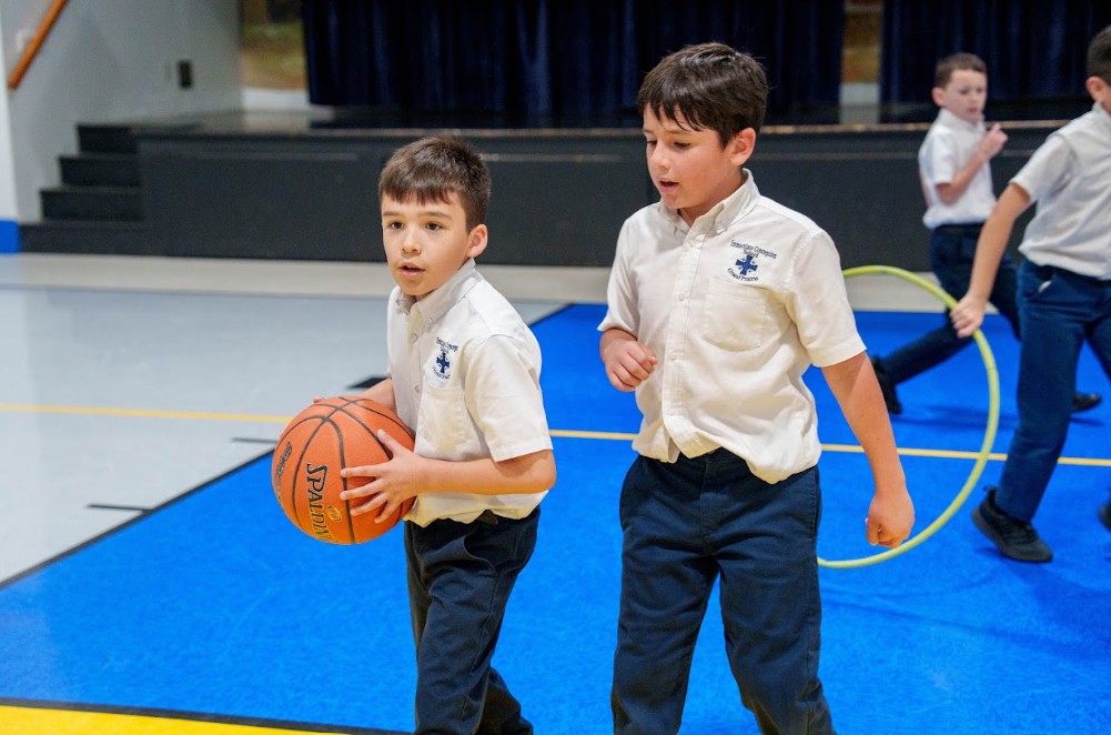 Students in school uniforms playing basketball in gymnasium