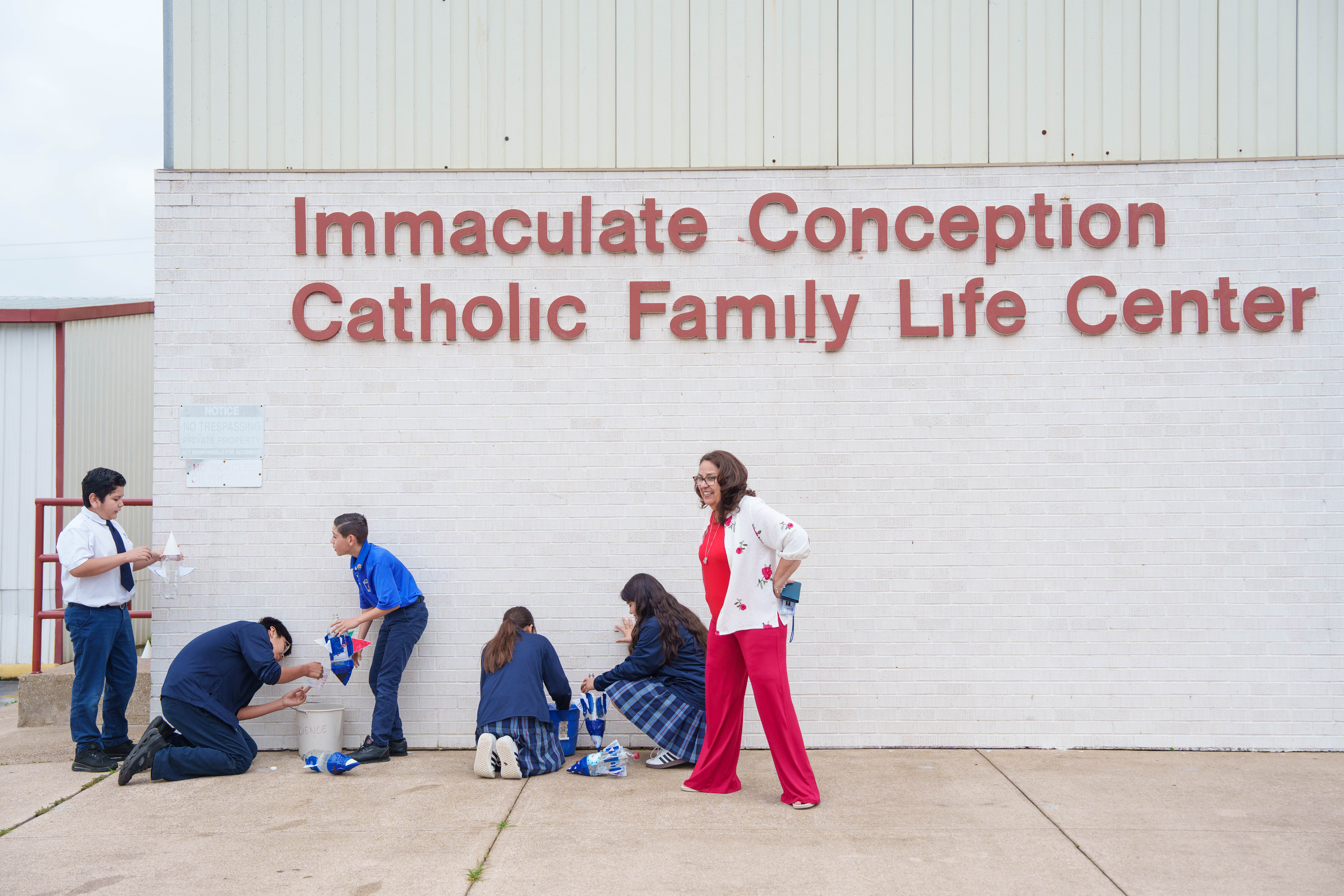 Students and teacher doing service work outside Immaculate Conception Catholic Family Life Center