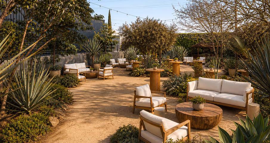 Outdoor garden seating area with wooden chairs, sofas, round tables, and potted plants under string lights.