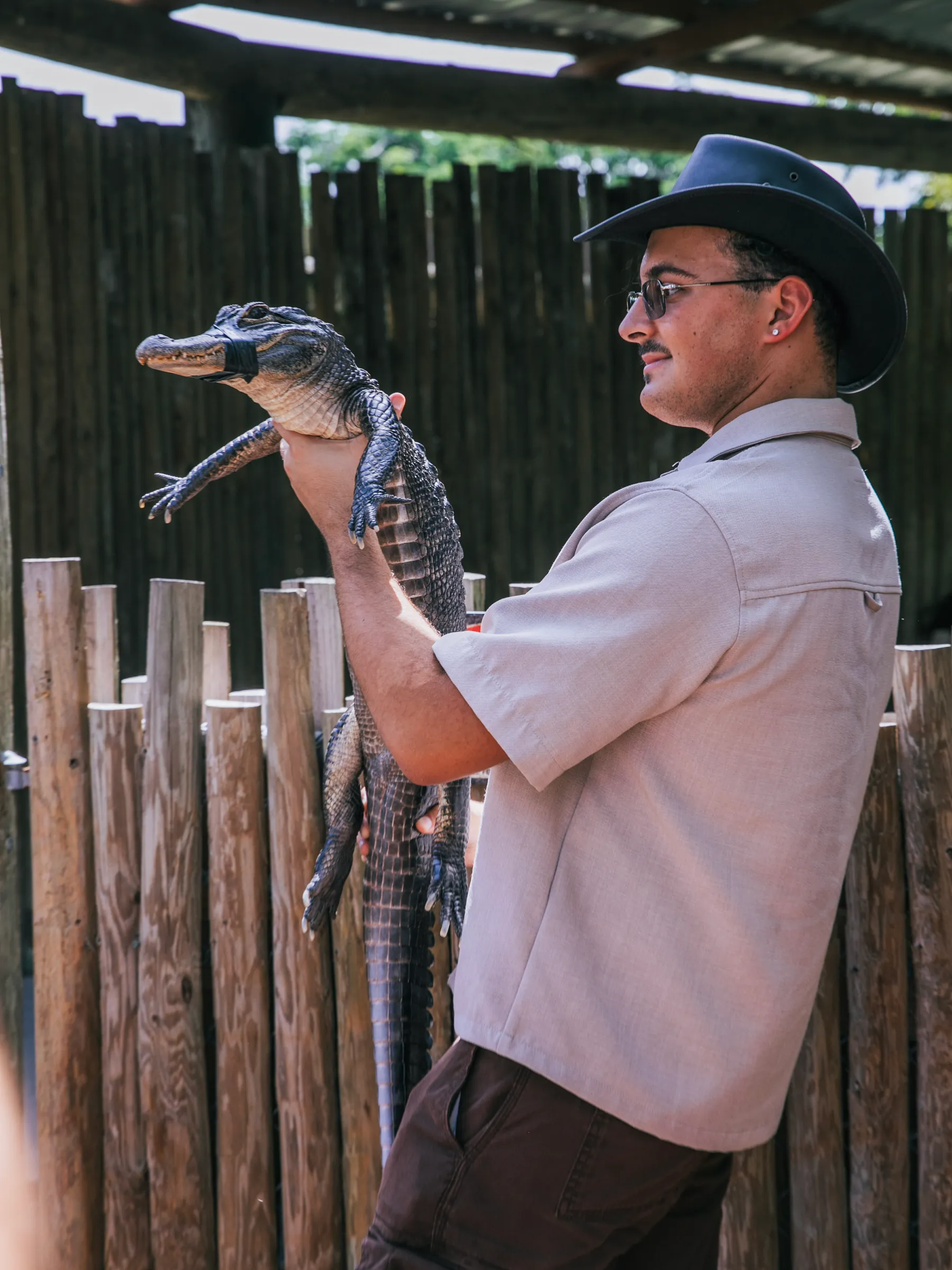 Animal team member in a cowboy hat holding an alligator on the encounter deck
