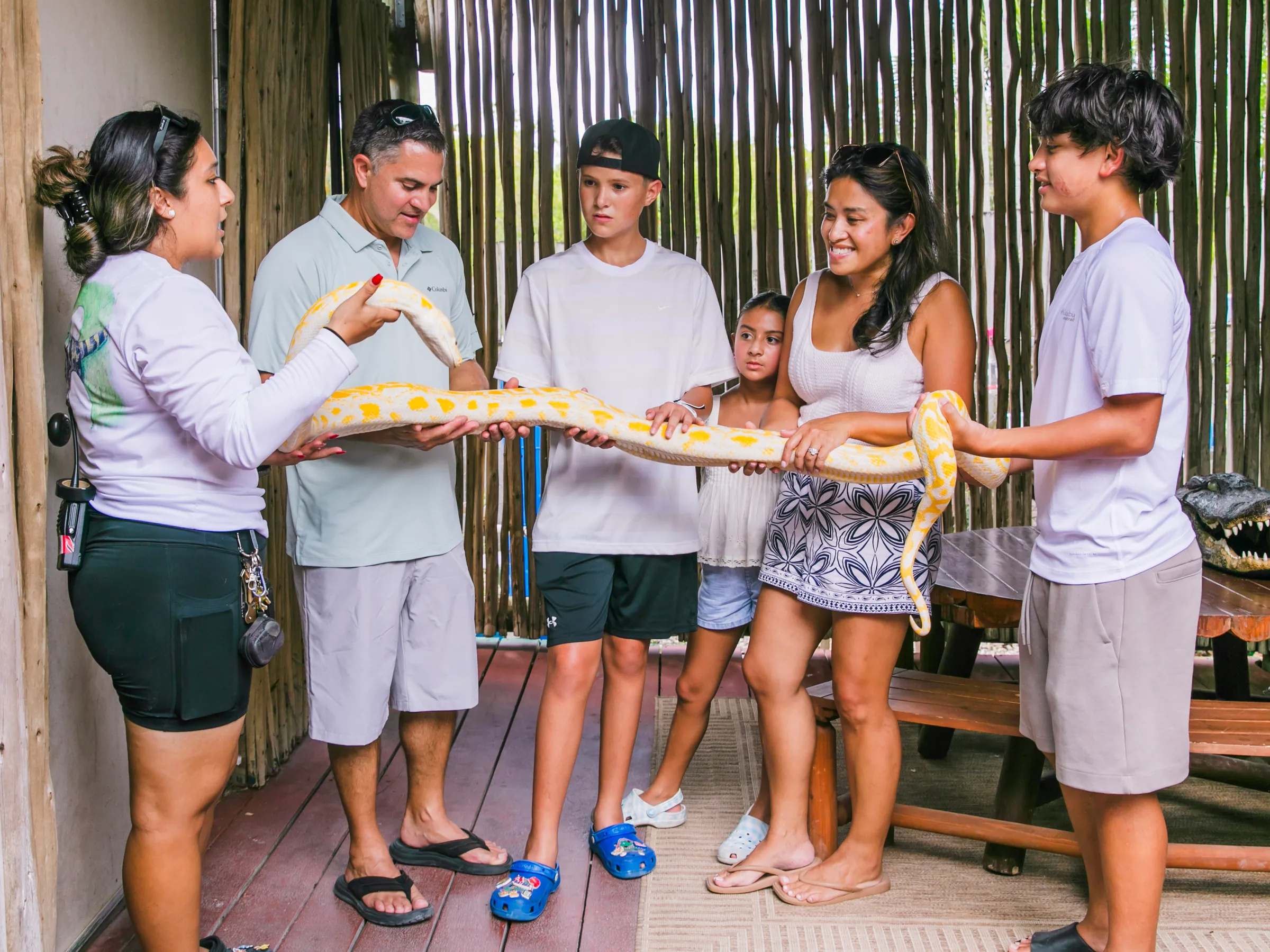 Parents and three kids lined up holding an albino python on the reptile deck during the VIP Experience