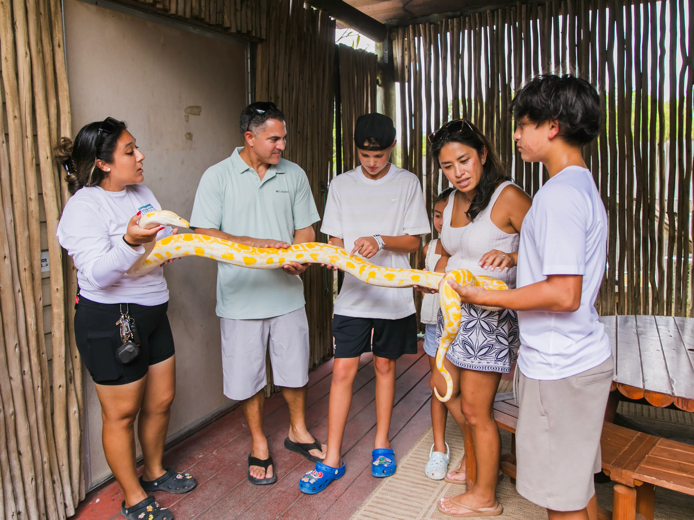 Family of five holding an albino python with help from an animal team member during the VIP Experience at Everglades Alligator Farm