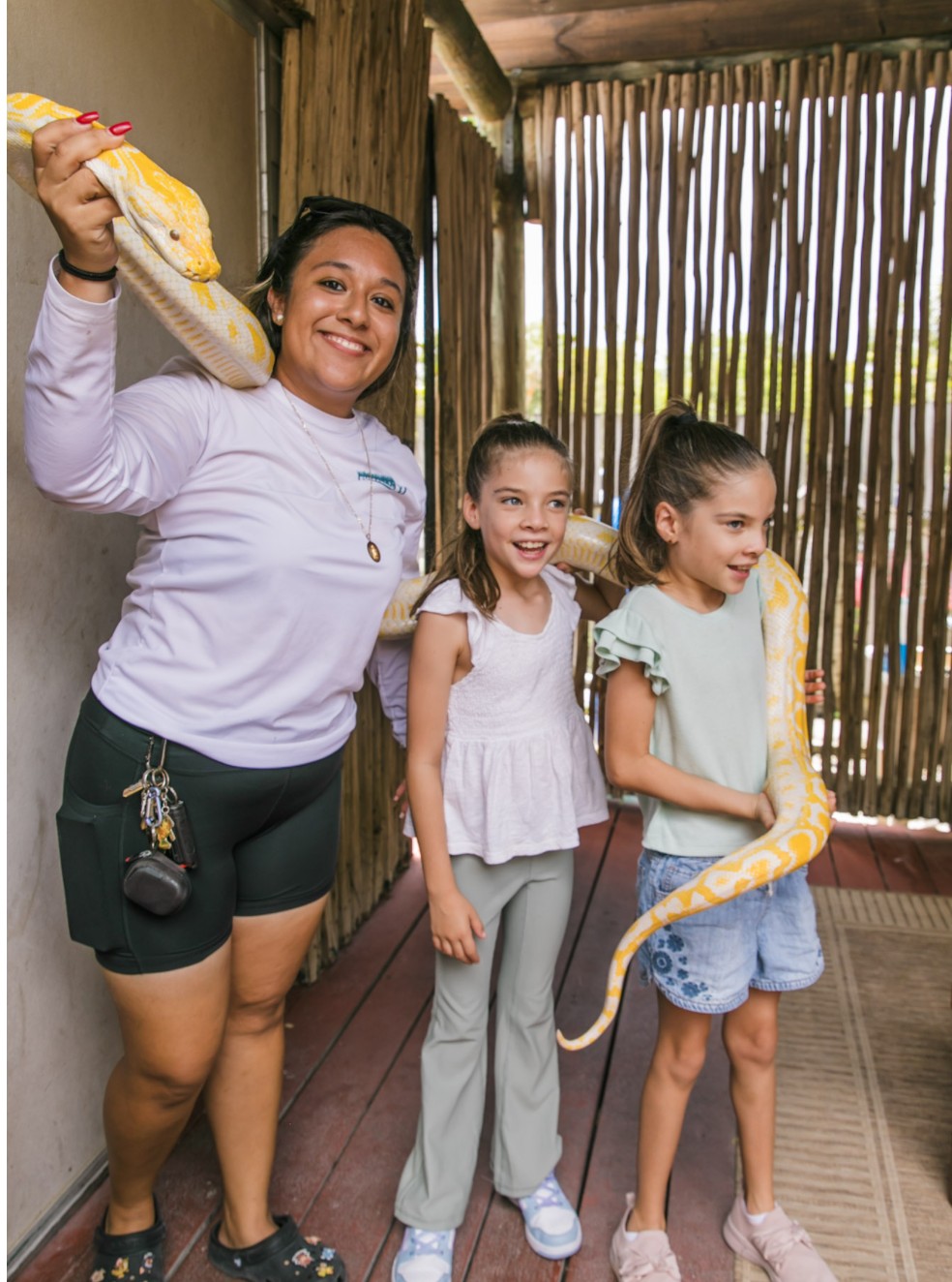 Guest holding a large snake with an animal team member and two children at Everglades Alligator Farm