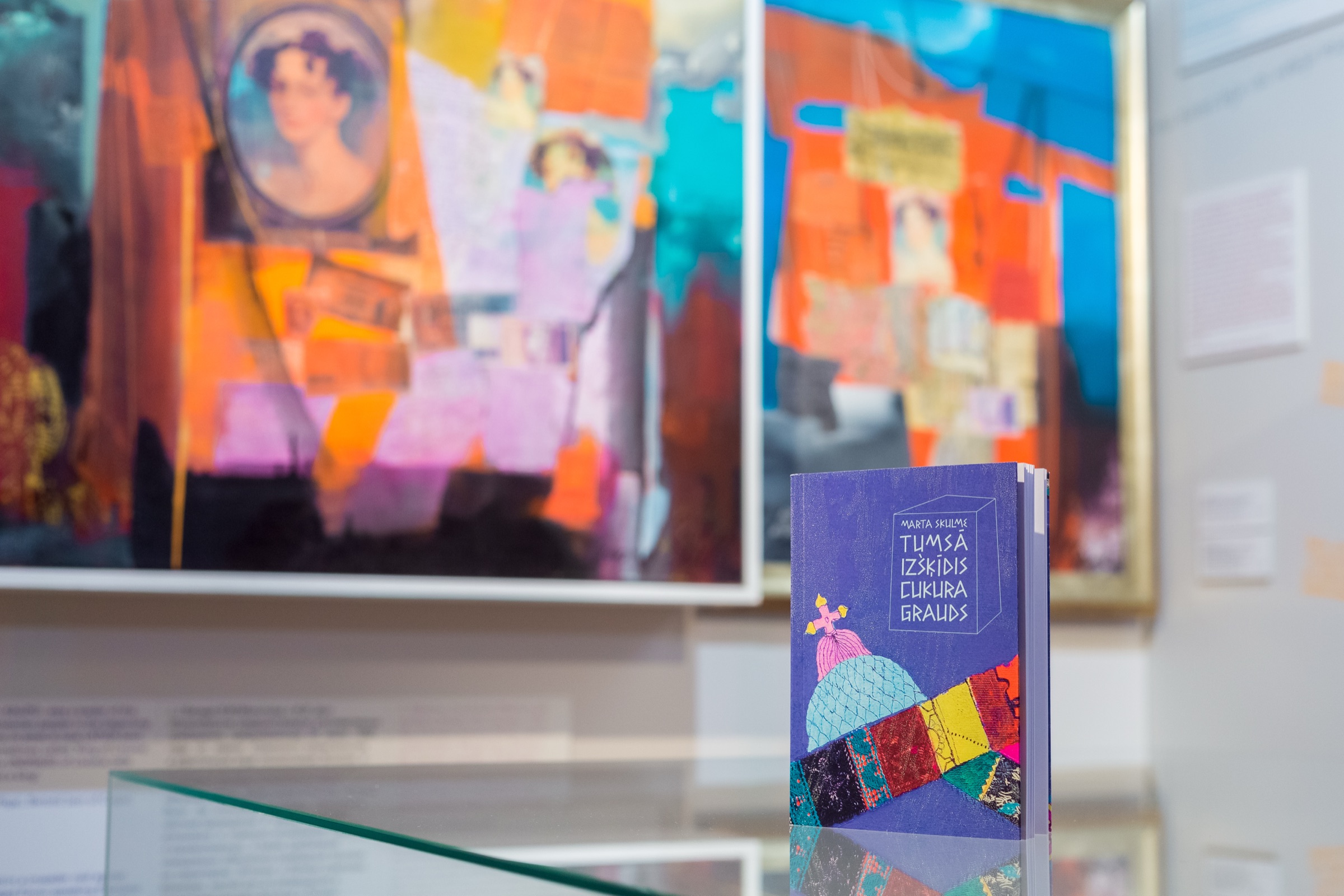 Grāmata izstādes telpā uz gleznu fona