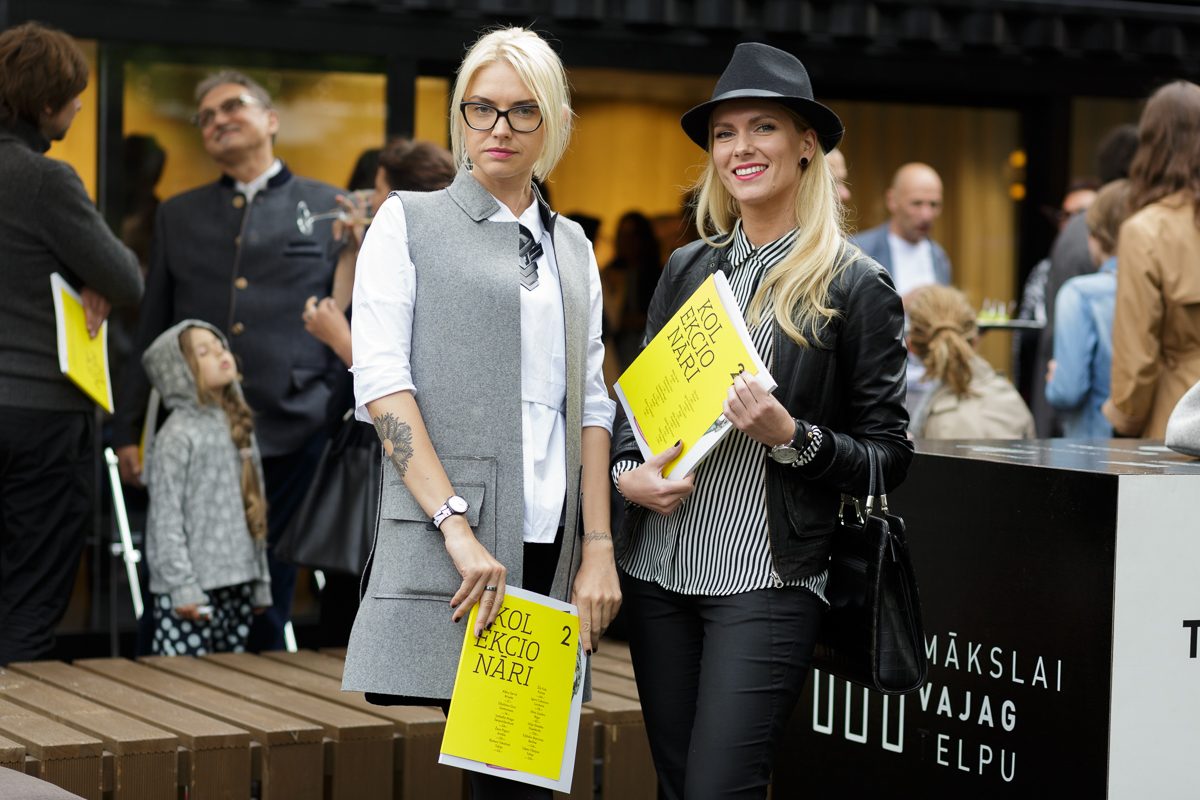 Divas sievietes ar dzelteniem izdevumiem „Kolekcionāri 2” rokās pie konteinera ar uzrakstu „Mākslai vajag telpu”
