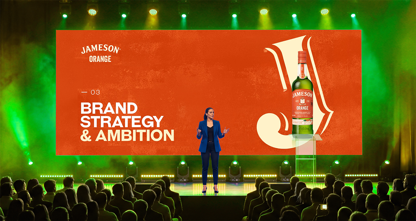Woman in blue suit presenting on stage with a large 'Jameson Orange' slide and bottle image behind her.