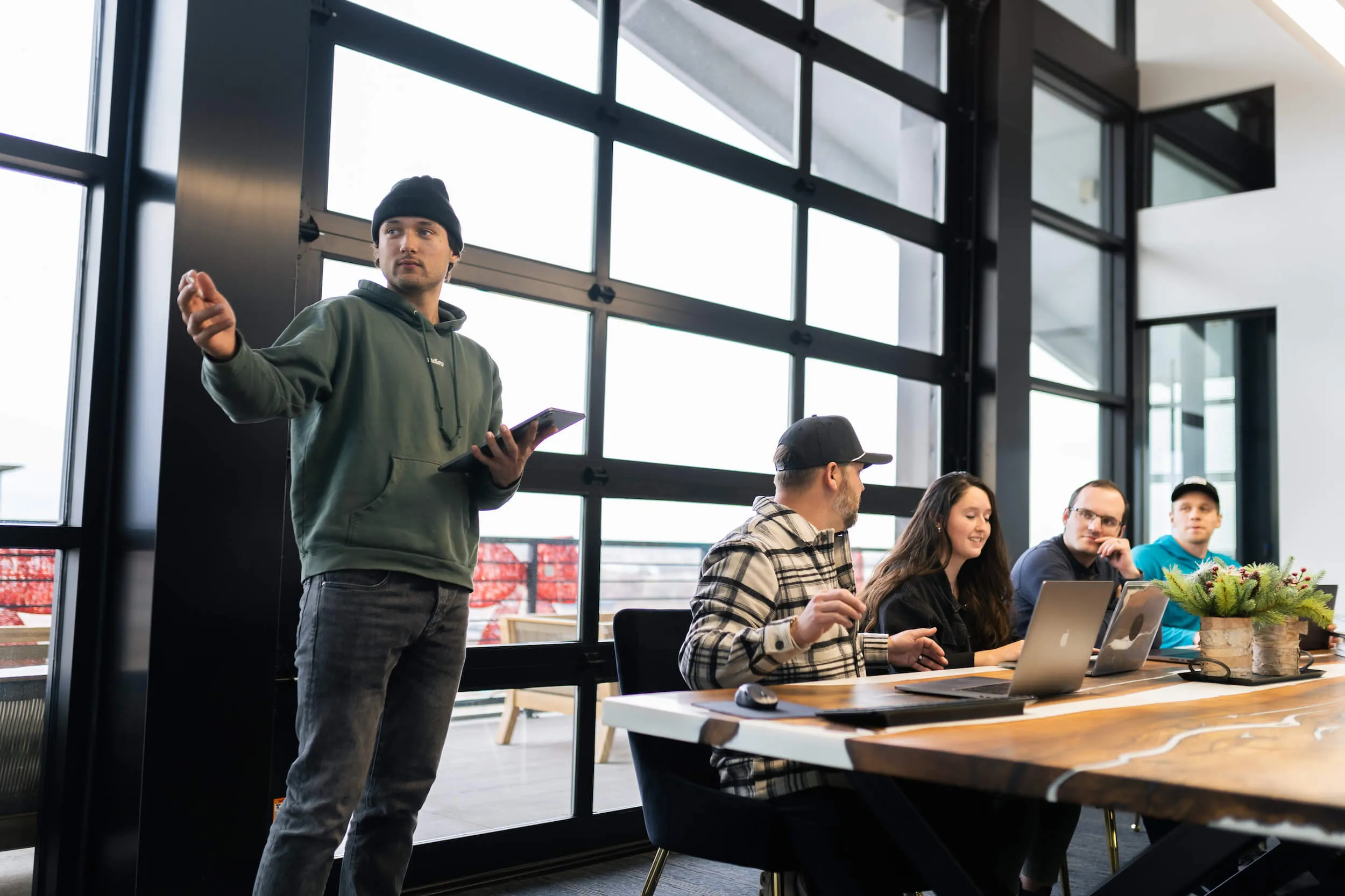 A PHENYX team member presenting from a tablet to four colleagues seated at a conference table