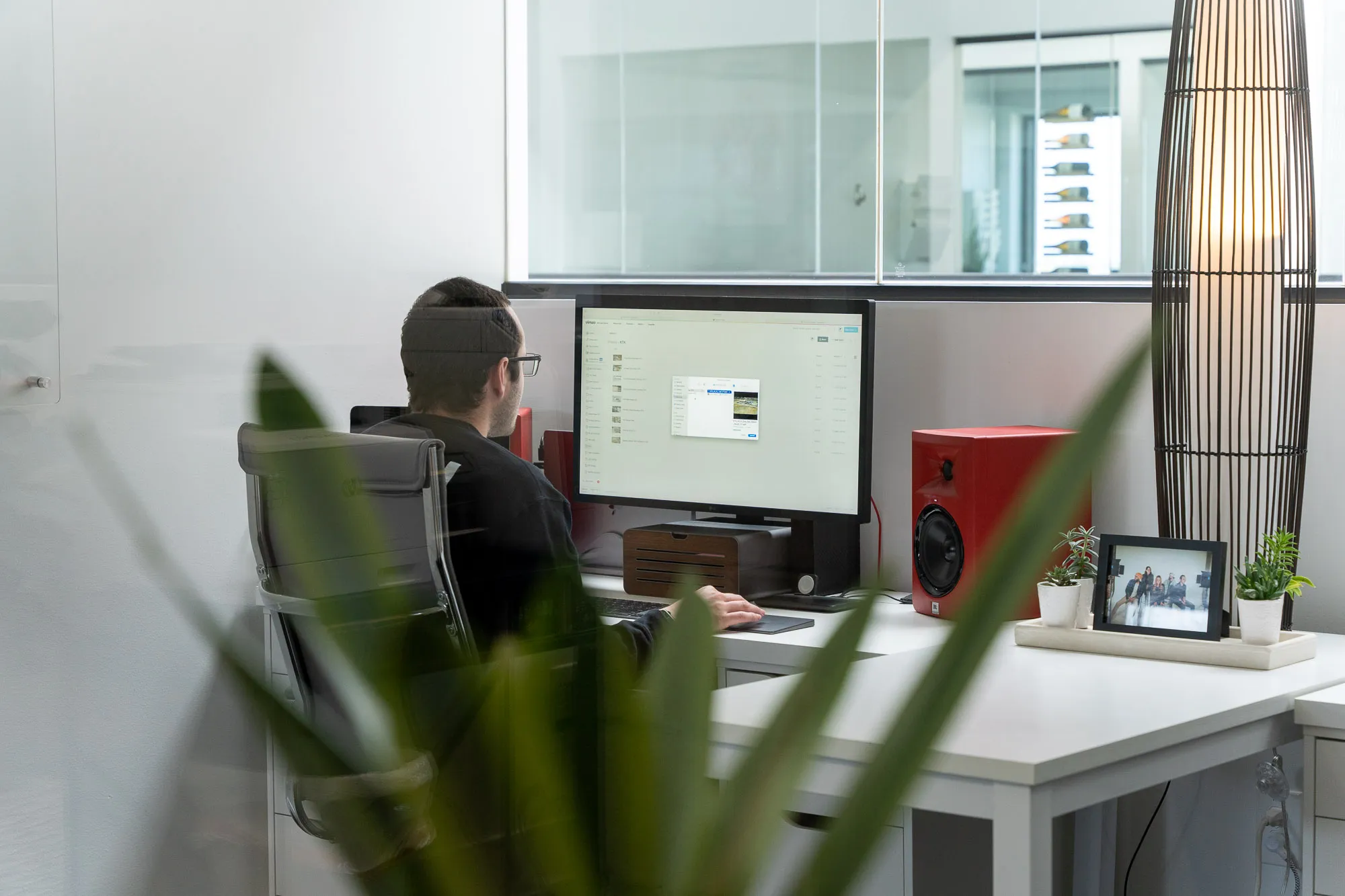 A PHENYX team member at their desk reviewing a video library on a large monitor