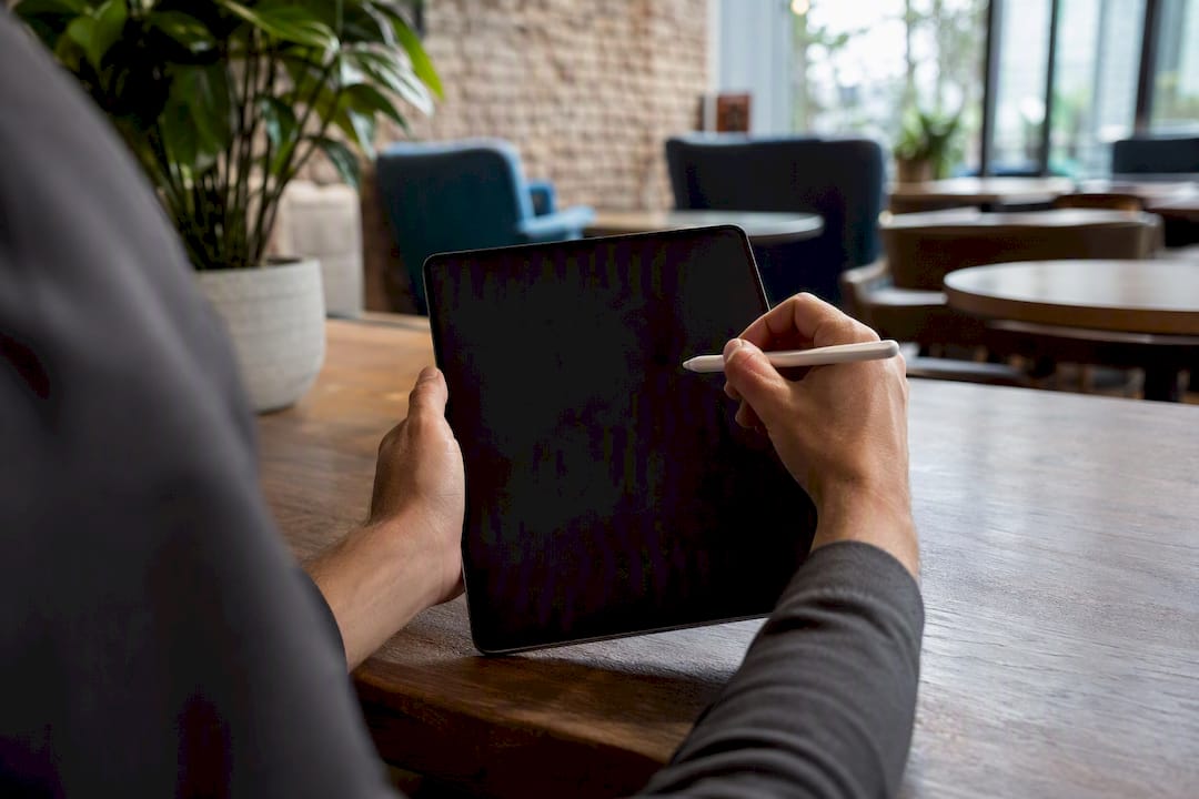 Hands holding stylus over tablet in planning gesture