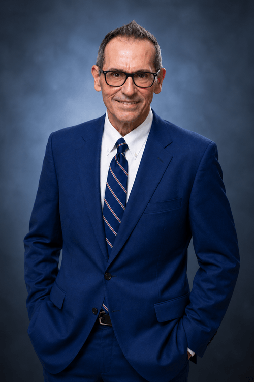 Richard Casolari, CFP, in a navy suit and striped tie against a dark studio background
