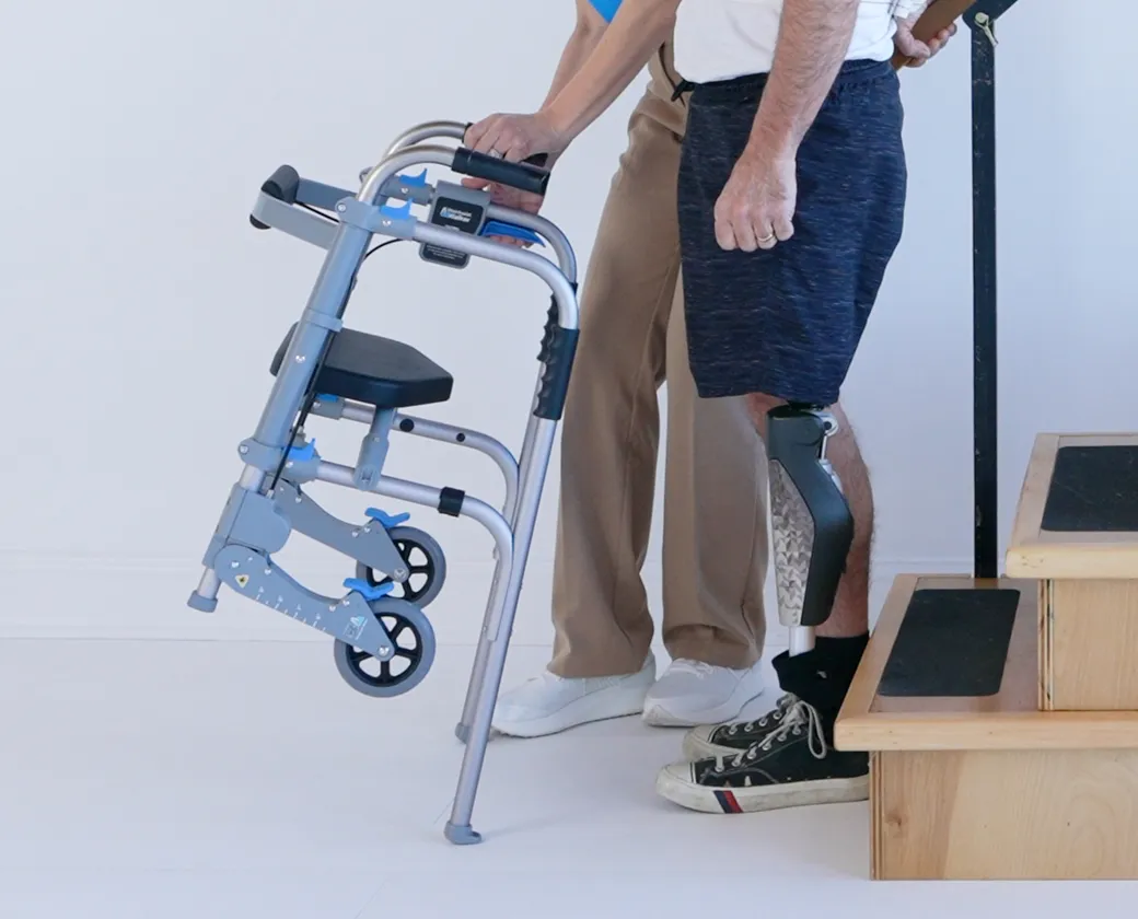 An older woman walking with the StairAssist Walker in her home while a caregiver supports her with a gait belt