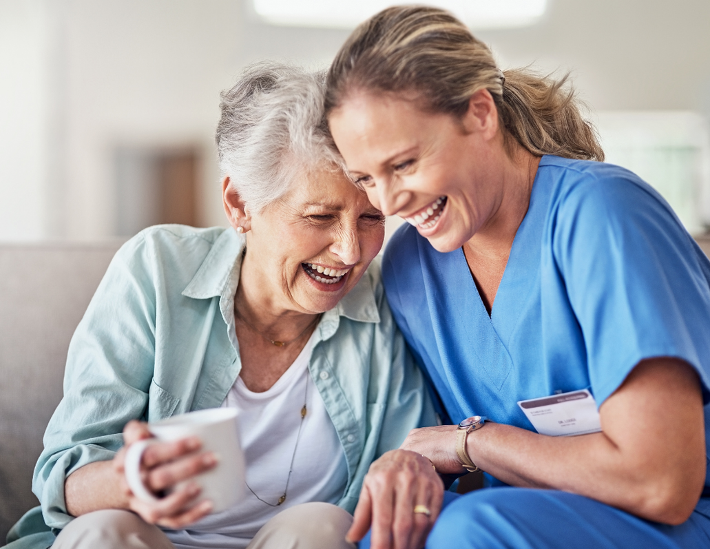 A nurse and an older woman laughing together