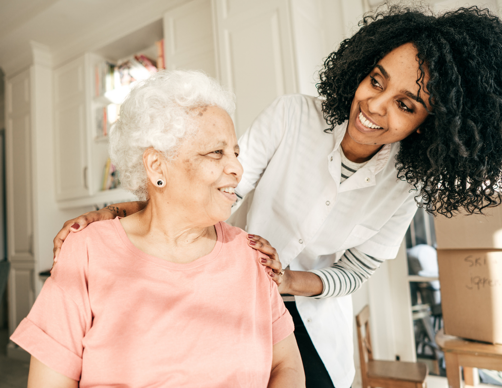 A caregiver smiling with an older woman at home