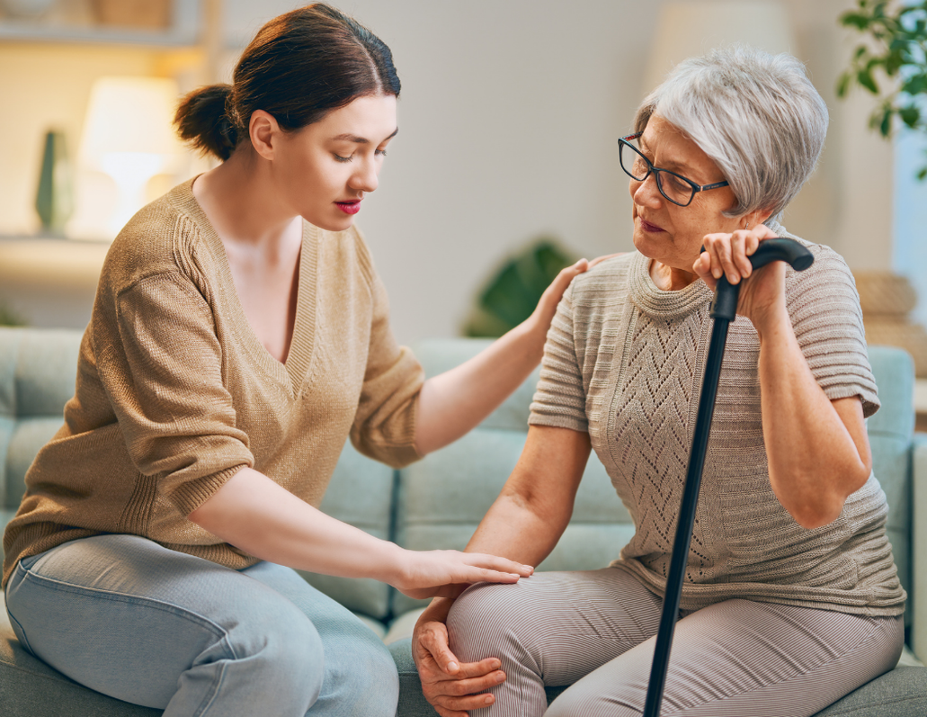 A young woman comforting an older woman with a cane