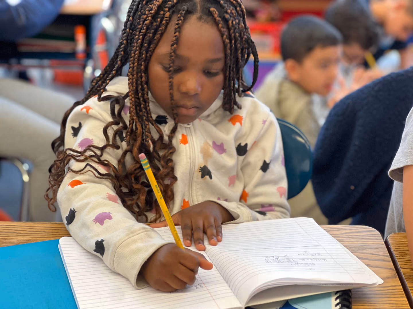 Student writing in notebook with pencil during classroom activity