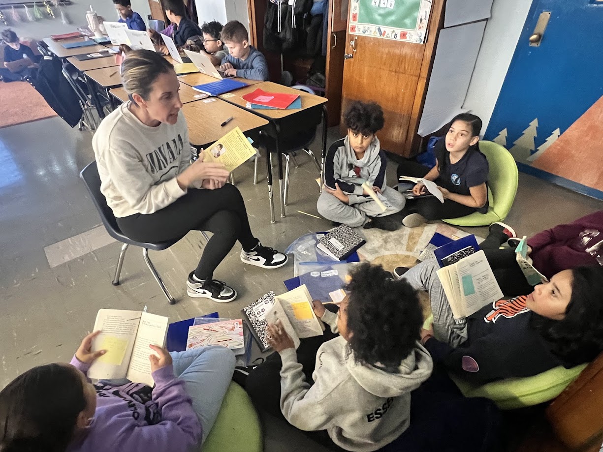 Teacher leading small group reading lesson with students on floor