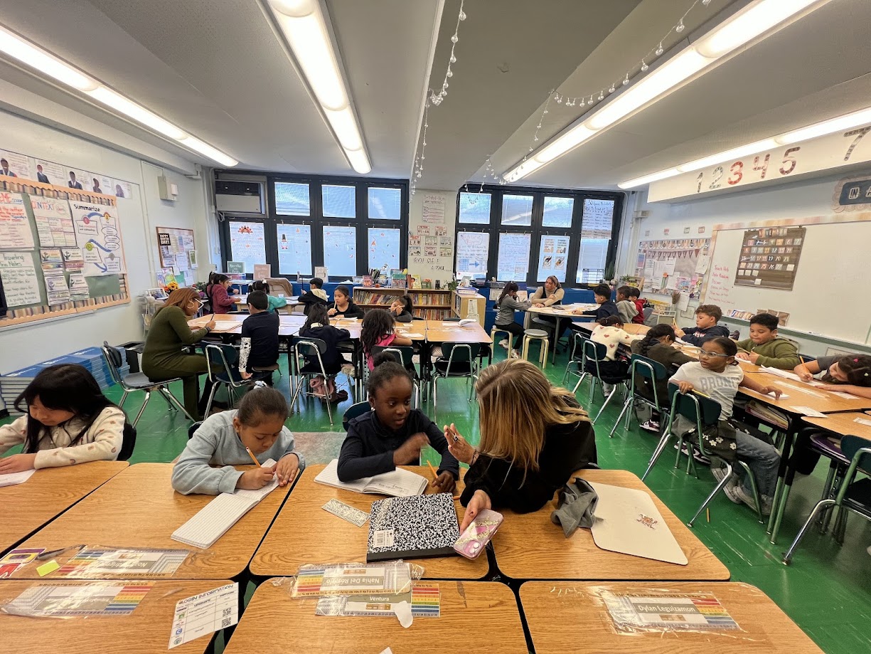 Students working at desks in a busy elementary school classroom