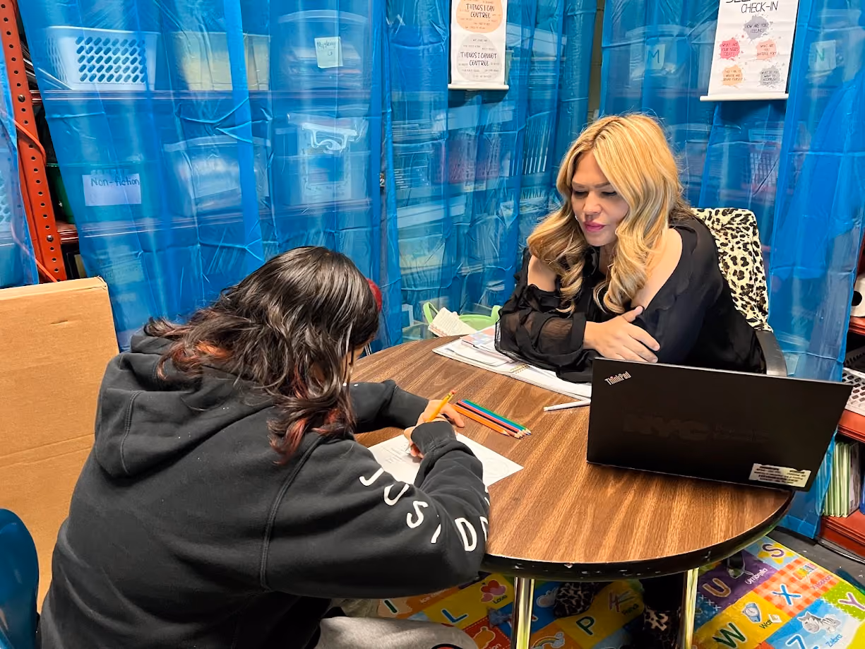 Teacher and student working together on a worksheet at a small table