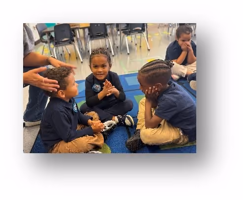 Three young students sitting on classroom floor interacting together