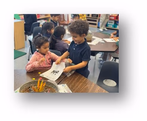 Two young students sharing and looking at a paper together in class