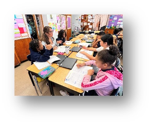 Students working together at classroom tables with open books