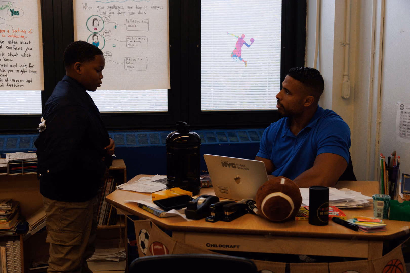 Teacher at desk speaking one on one with a student