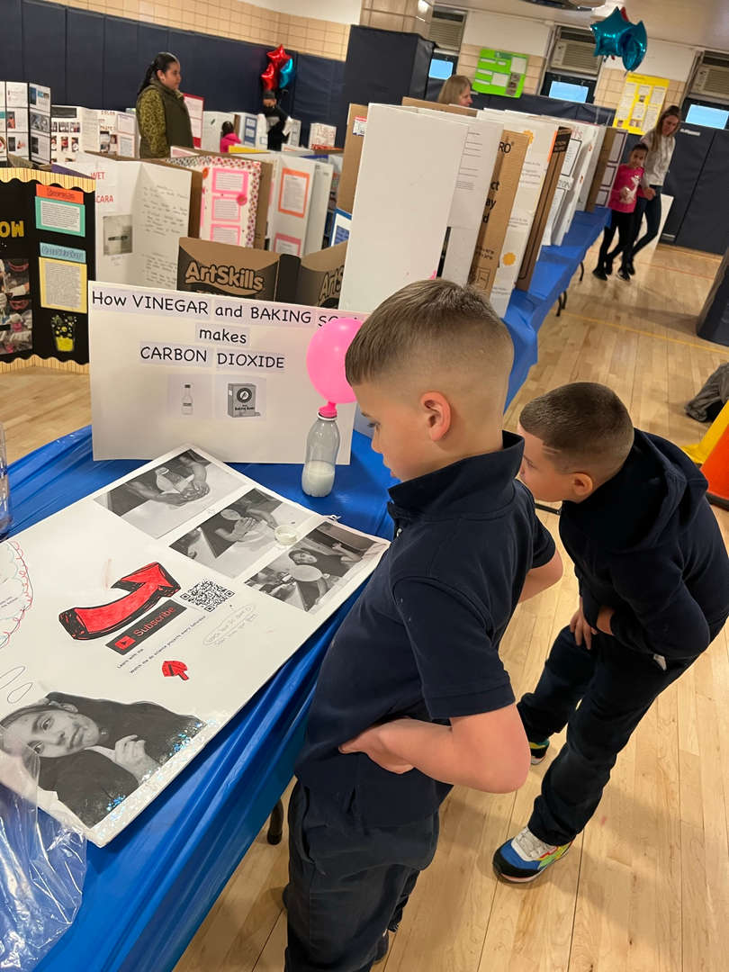 Two students viewing a vinegar and baking soda science fair project