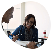 Teacher smiling while reviewing student work at a desk