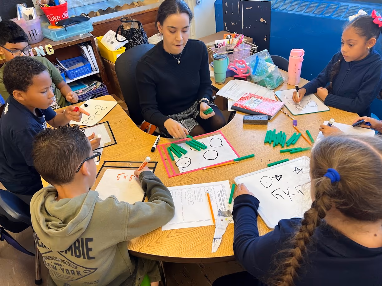 Teacher leads small group math lesson using manipulatives and whiteboards