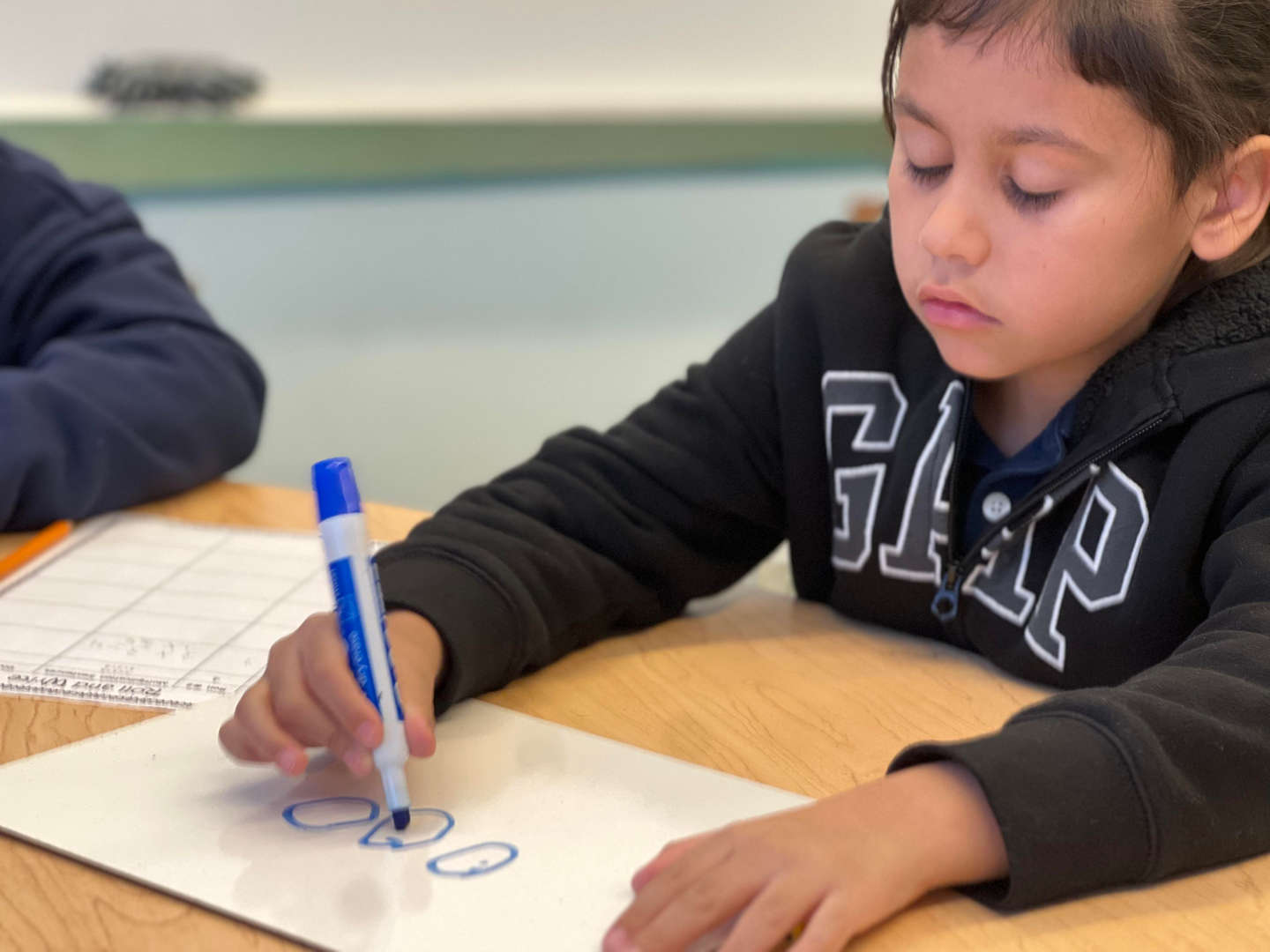 Student writing circles with blue marker on white paper