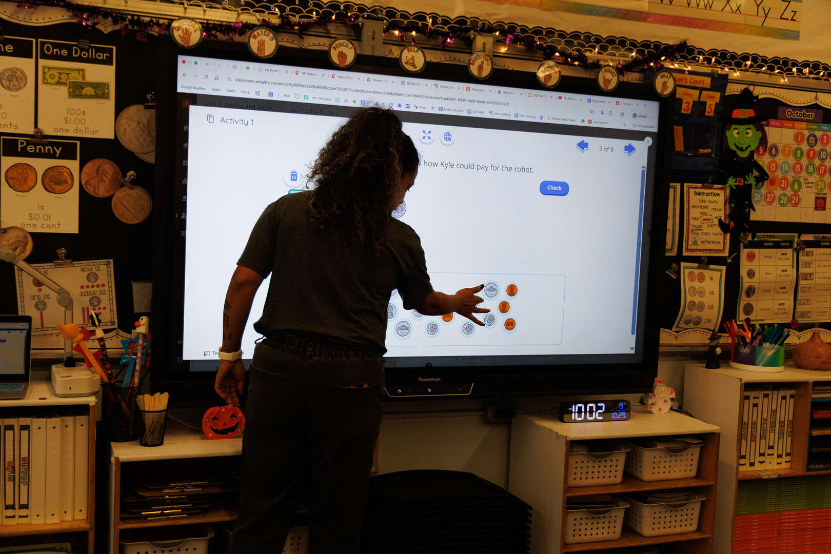 Teacher interacting with a smartboard during a math coins lesson