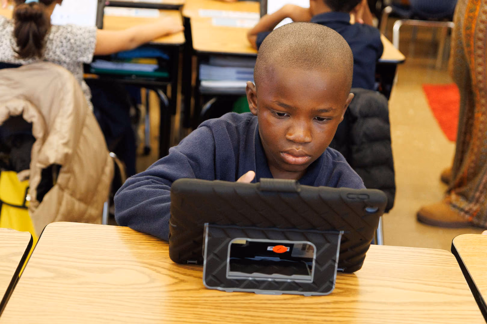 Student focused on tablet device during classroom learning activity
