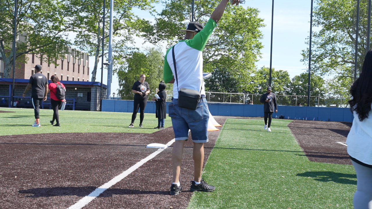 Student throwing a ball on an outdoor baseball field during activity