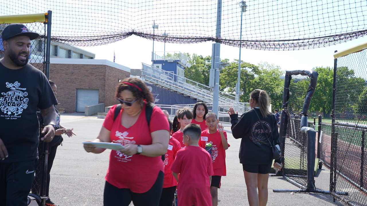 Students and adults in red Field Day shirts at outdoor sports facility