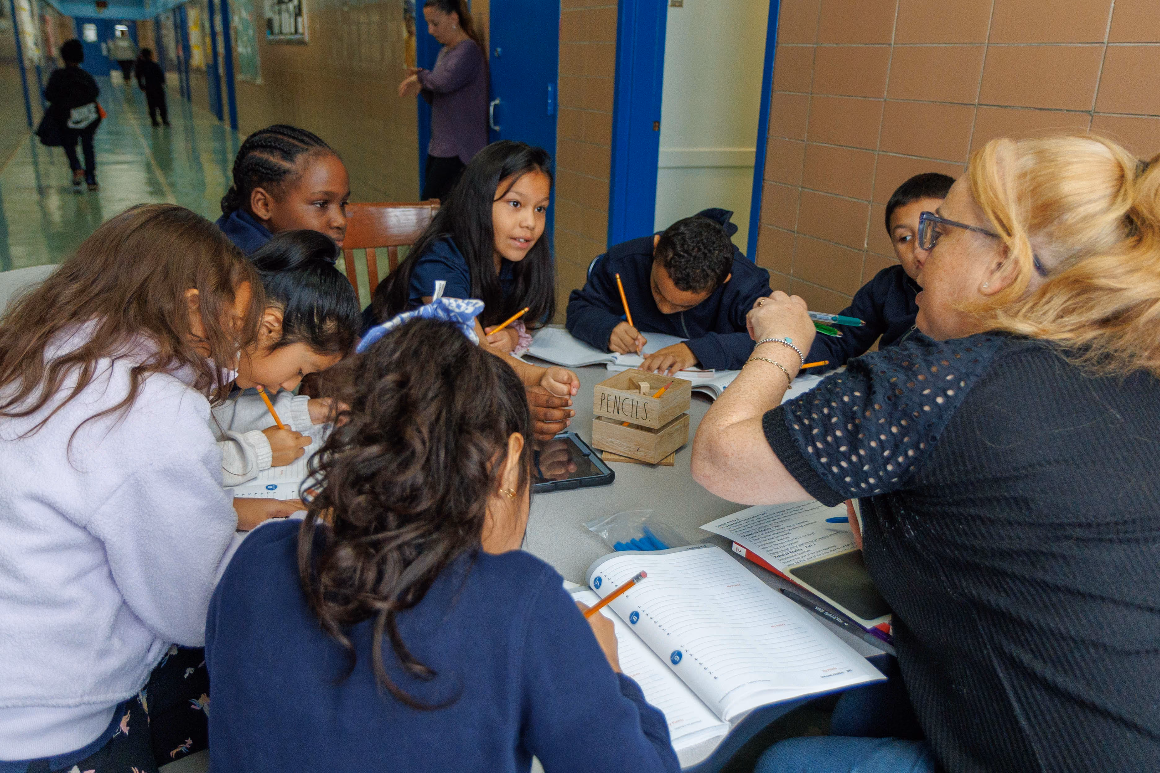 Teacher working with small group of students in school hallway