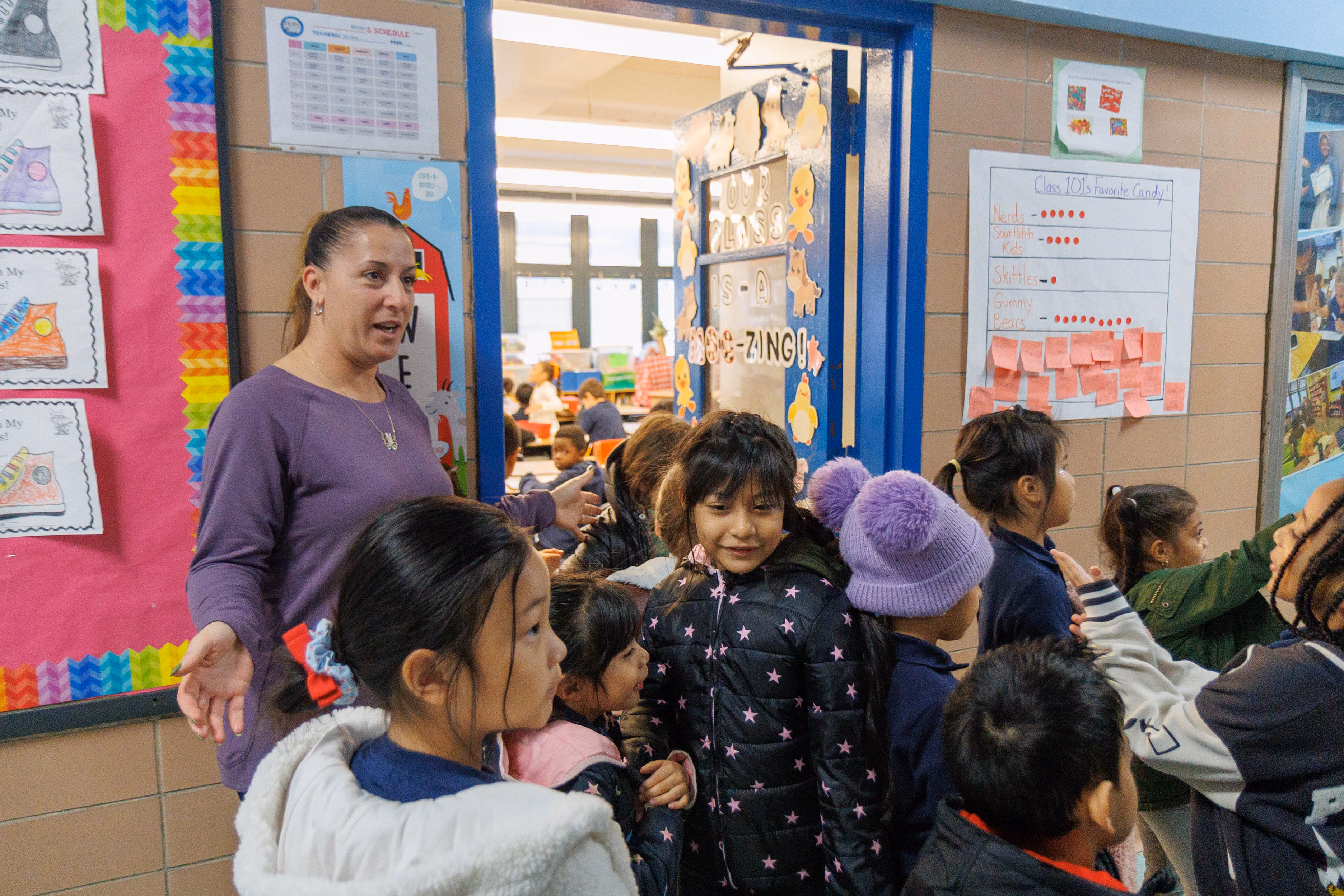 Teacher guiding young students through a colorful classroom doorway