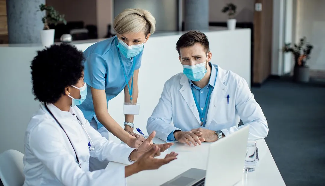 group-medical-experts-talking-while-using-laptop-meeting-hospital 1