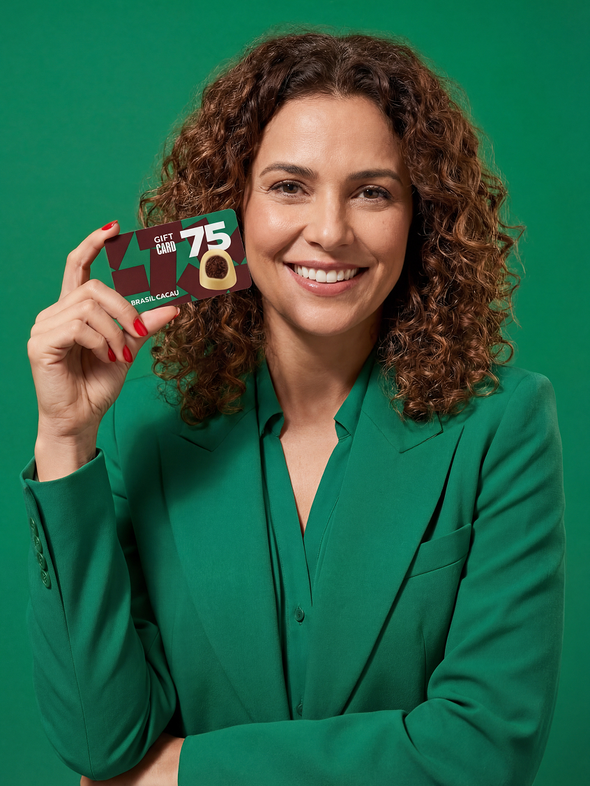 Mulher sorridente segurando cartão-presente Brasil Cacau, sobre fundo verde