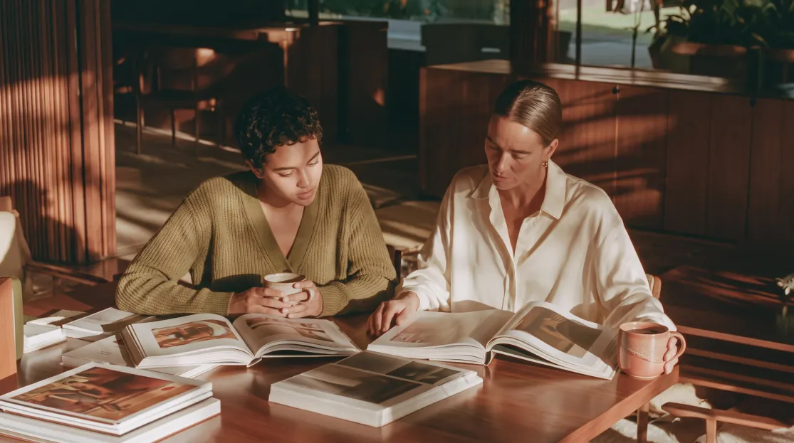 Duas mulheres lendo livros em uma mesa de biblioteca