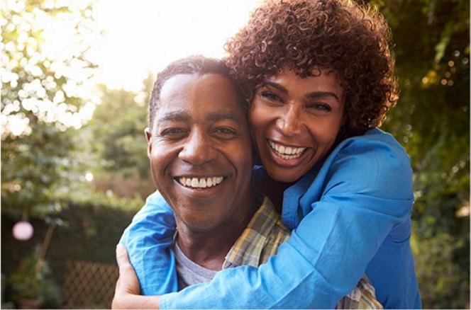 Two IDLife customers outdoors, one with an arm around the other, both smiling
