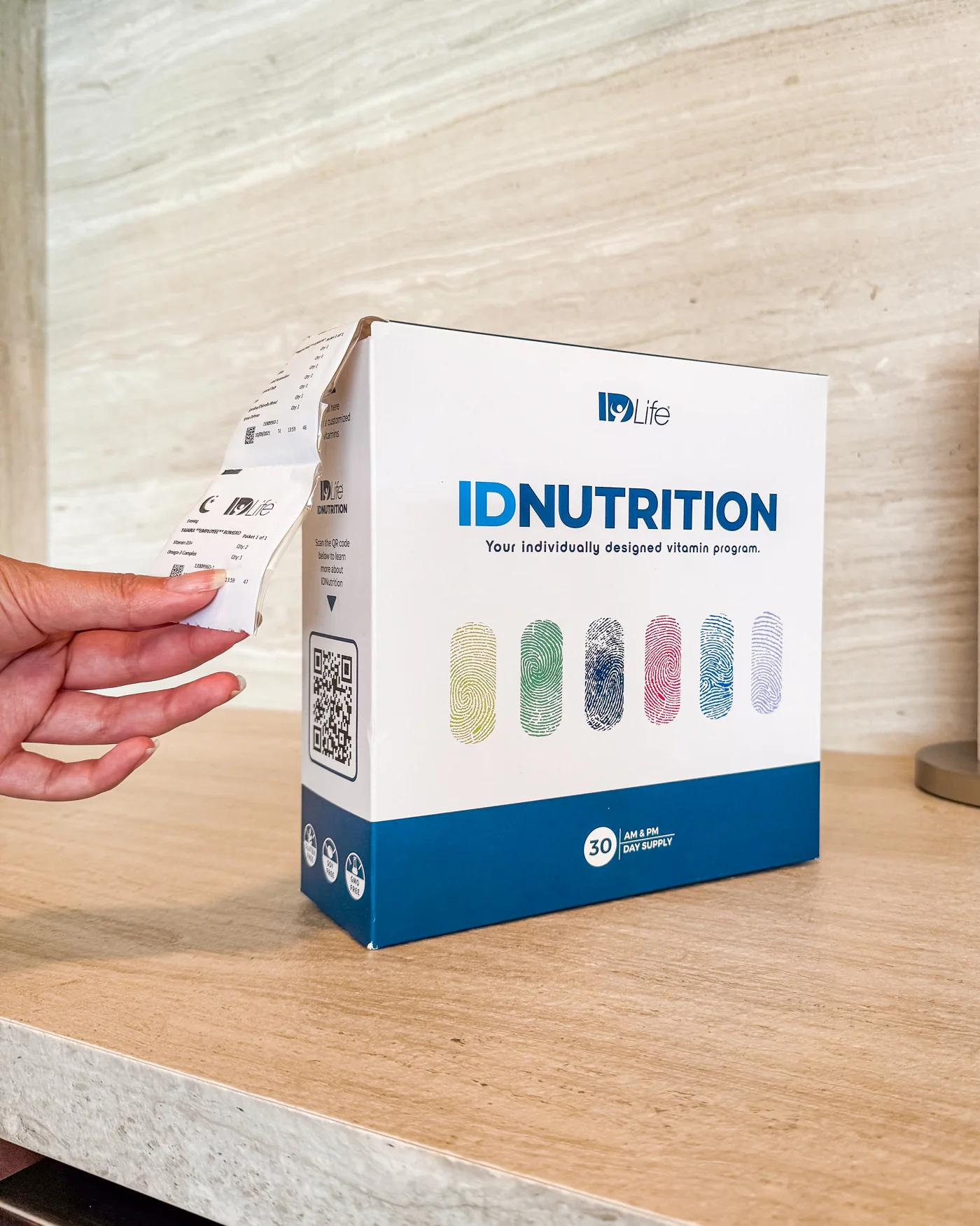 A daily vitamin packet being pulled from an IDNutrition box on a kitchen counter