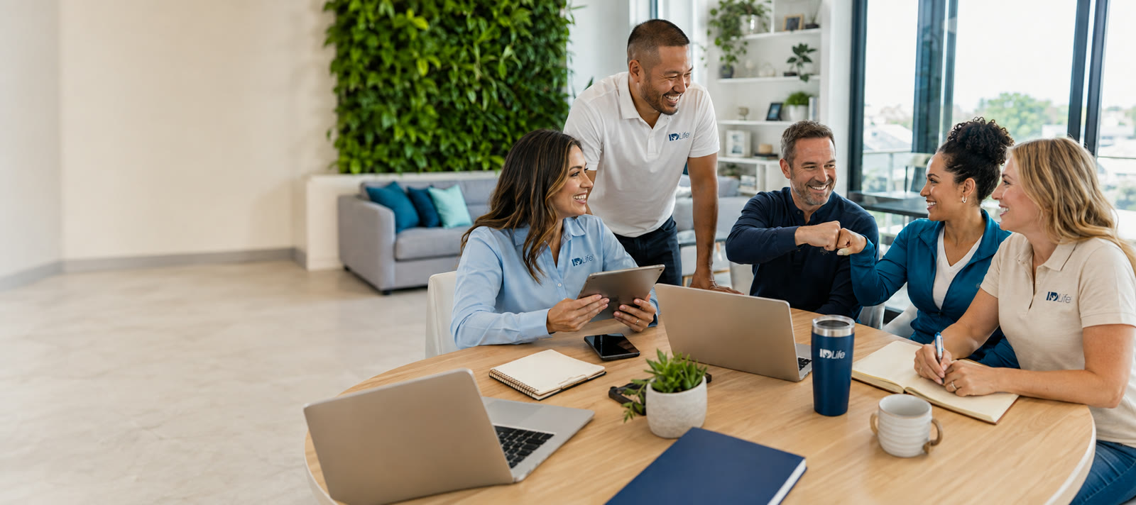 Five Associates working together around a table with laptops
