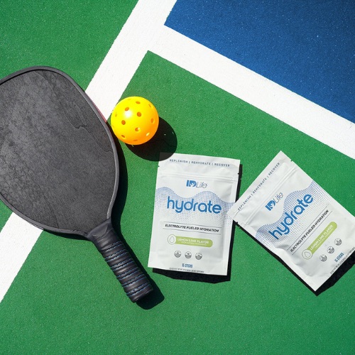 Two Hydrate Lemon Lime bags beside a pickleball paddle and ball on a court