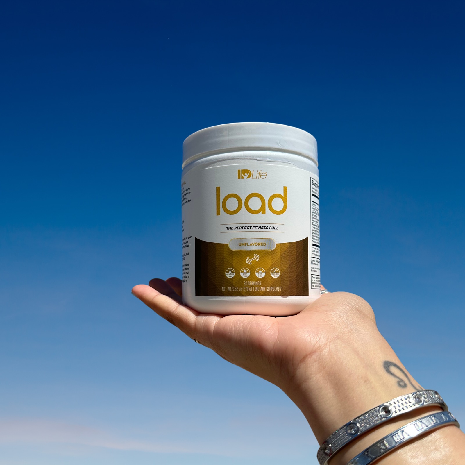 A hand holding a Load jar up against a clear blue sky