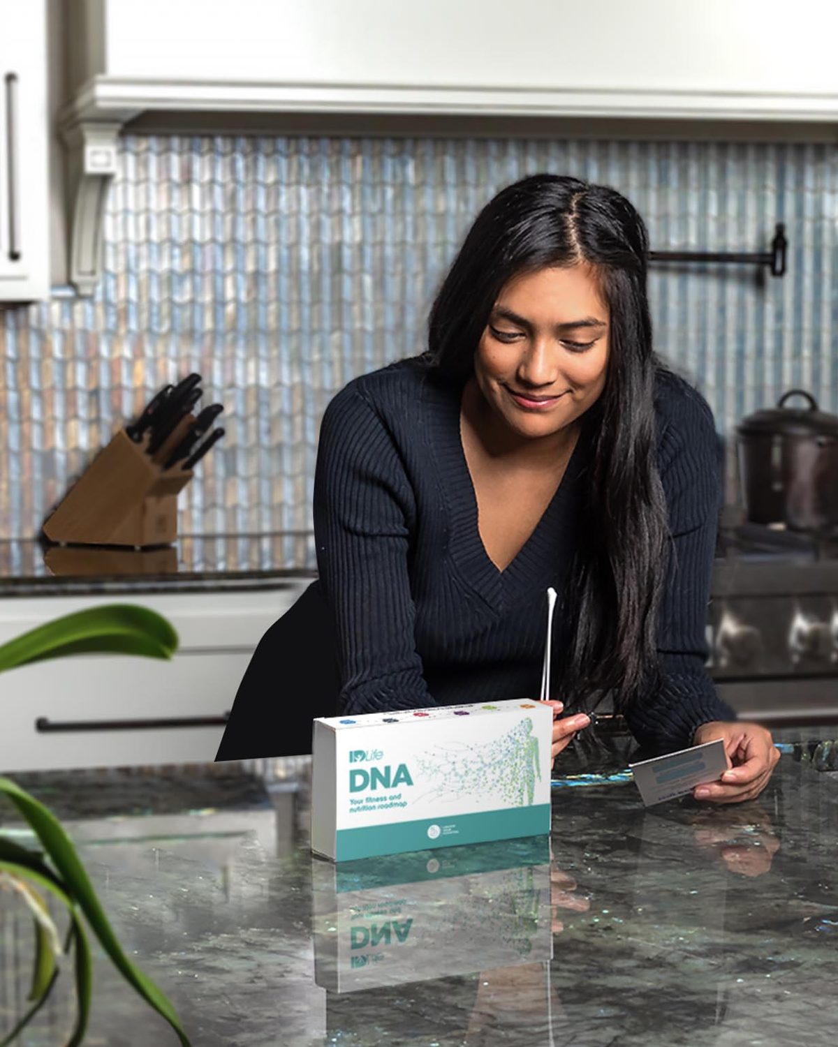 A woman at her kitchen island opening the IDLife DNA kit and holding the collection swab