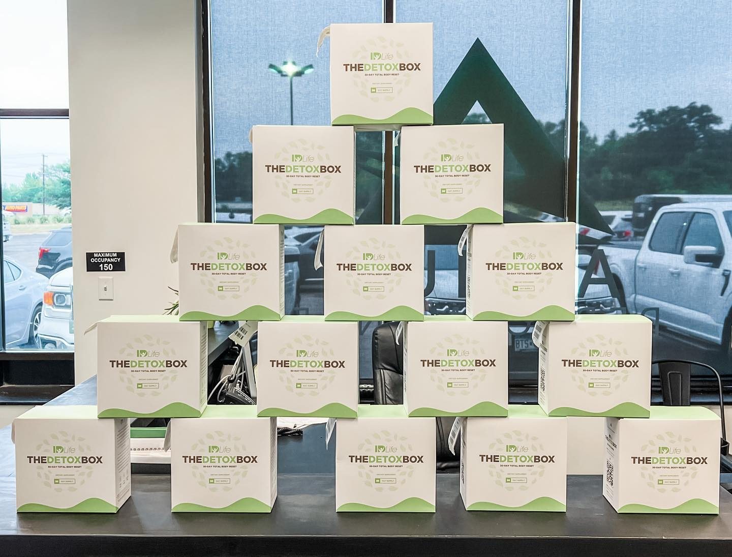 A pyramid of fifteen Detox Boxes stacked on a counter in front of a window
