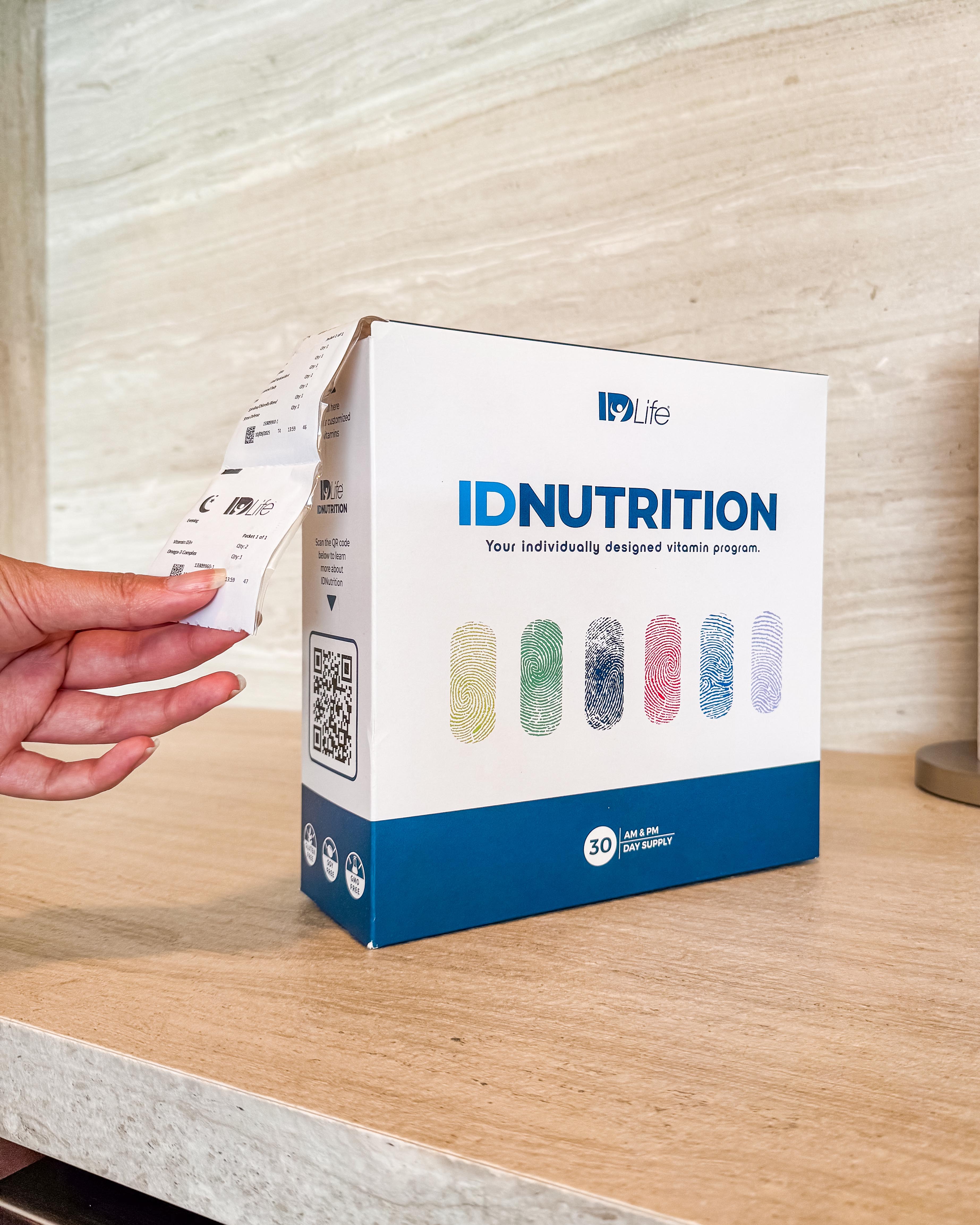 A daily vitamin packet being pulled from an IDNutrition box on a kitchen counter